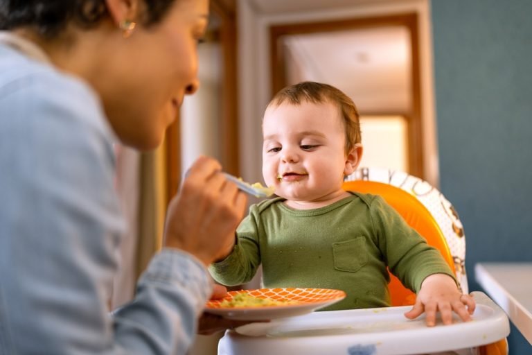 Joyful,Baby,Boy,In,Green,Outfit,Being,Spoon-fed,By,Loving